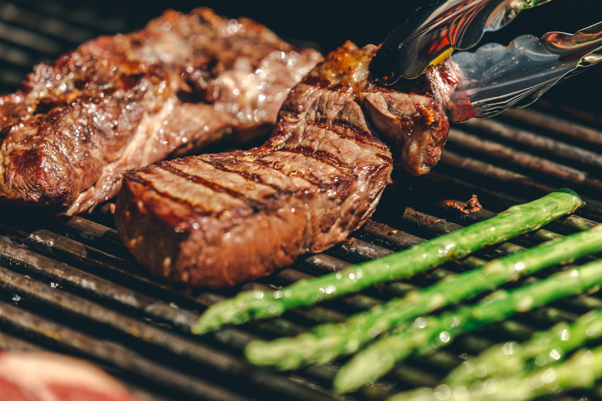 Saftig gebratenes Steak auf dem Grill mit grünem Spargel